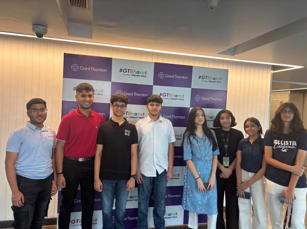 Eight students from the GTernship programme standing in front of a Grant Thornton backdrop