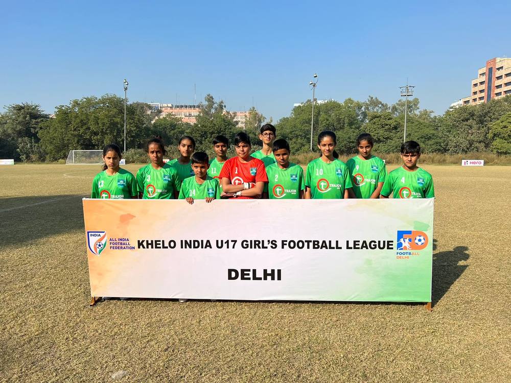 A Delhi team in green kit behind a Khelo India U17 Girls' Football League banner