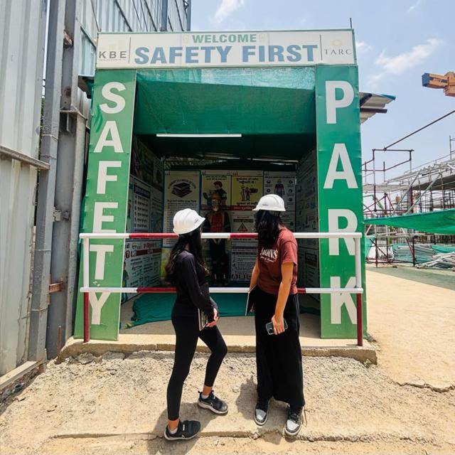 Two volunteers in hard hats looking at a construction site safety gate